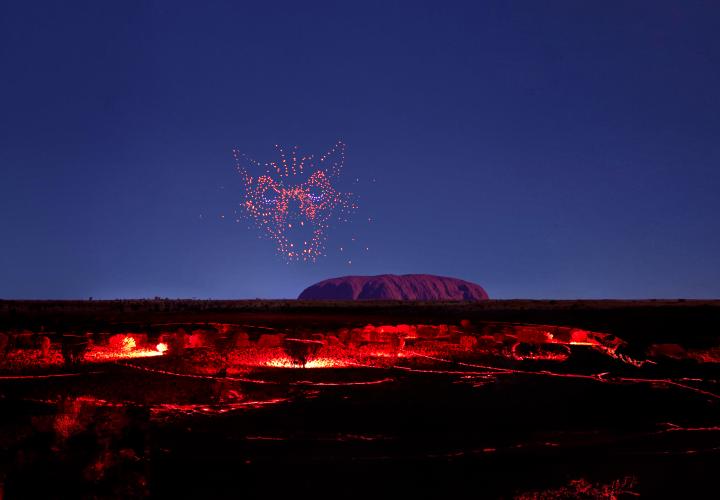/Drones creating Kurpany in the outback sky in front of uluru over the landscape during Wintjiri Wiru